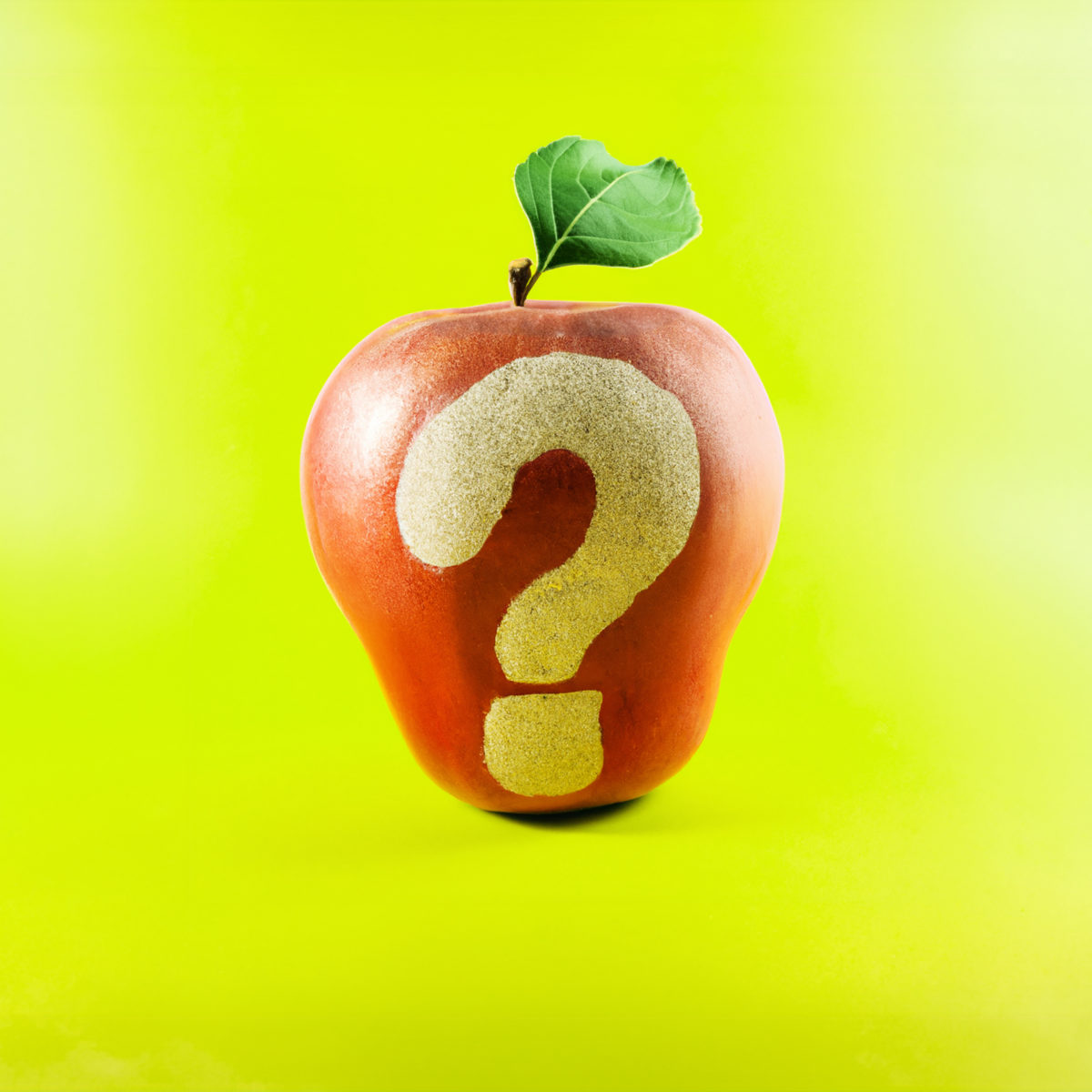 Pomme rouge avec un point d'interrogation sans peau, sur fond vert pomme.